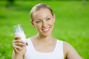 Ragazza con una bottiglia di kefir su uno sfondo di erba verde