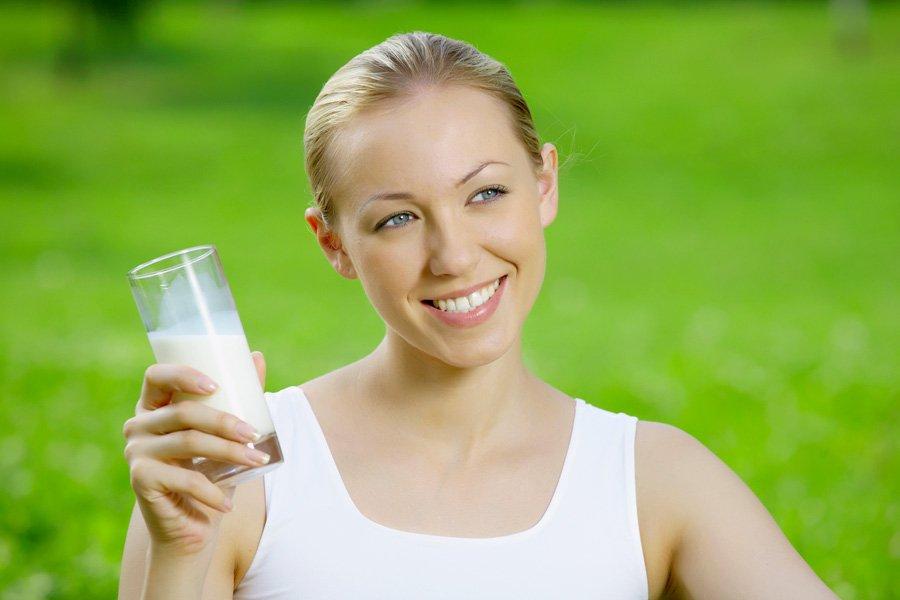 Ragazza con una bottiglia di kefir su uno sfondo di erba verde