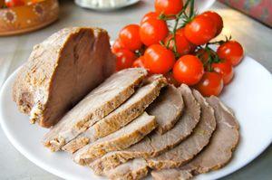 Porco bollito con i pomodori ciliegia su un piatto bianco