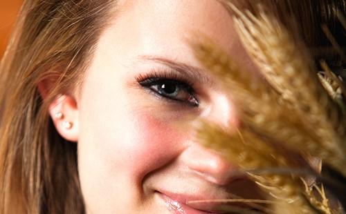 Ragazza che si nasconde dietro le spighette di grano