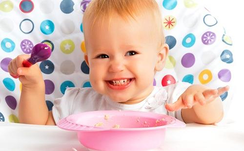 La ragazza ama il porridge in un piatto rosa