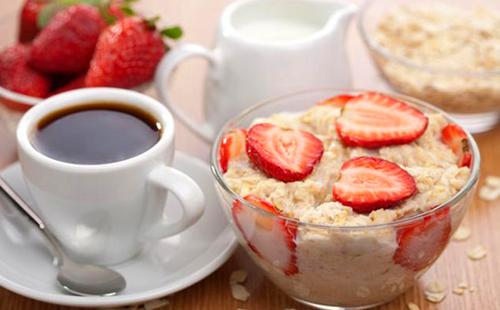 Colazione deliziosa con farina d'avena, fragole, panna e caffè