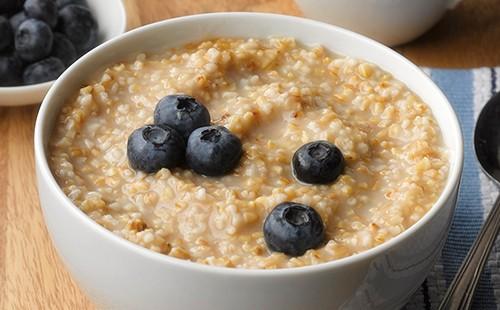 Le bacche blu-nere di mirtilli decorano la farina d'avena in una ciotola bianca