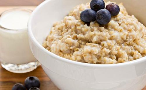 Farina d'avena vitaminica con un bicchiere di latte e mirtilli