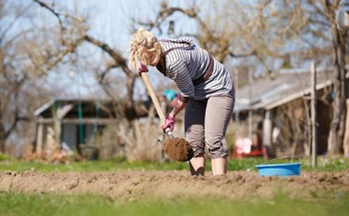 Donna che gocciola una pala nel giardino