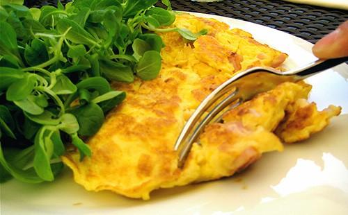 Frittata su un piatto, forchetta e verdure