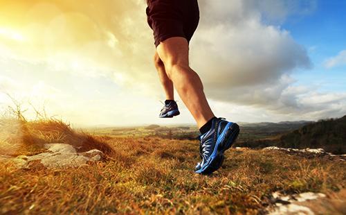 Un uomo in scarpe da ginnastica corre all'alba.