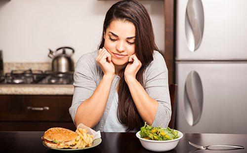 Ragazza dai capelli scuri guarda un hamburger