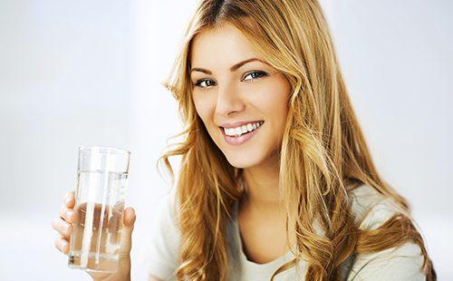 Ragazza sorridente che tiene un bicchiere d'acqua