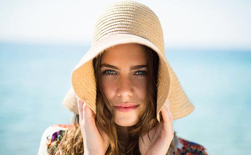 Ragazza al mare in un grande cappello