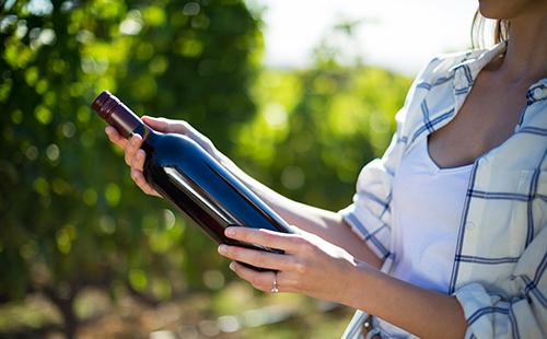 La donna in natura tiene una bottiglia di vino