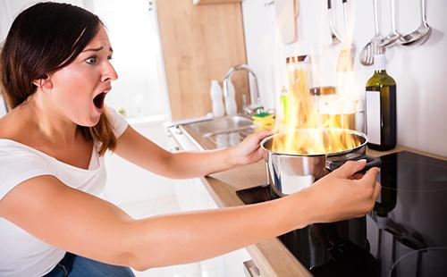 La donna con orrore guarda il cibo che brucia nella padella.