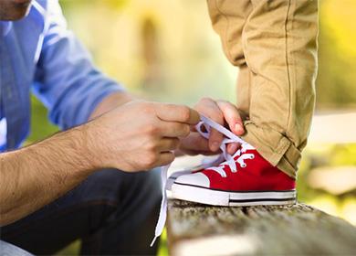 Padre che lega i lacci delle scarpe per suo figlio