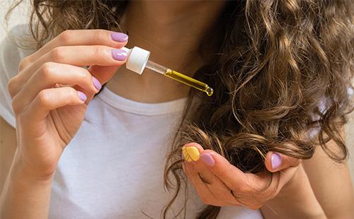 Olio gocciolante da una pipetta sui capelli