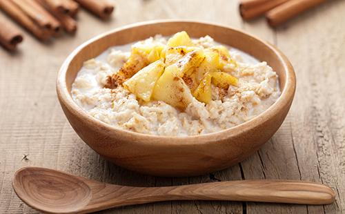 Farina d'avena con mele cotte in una ciotola di legno