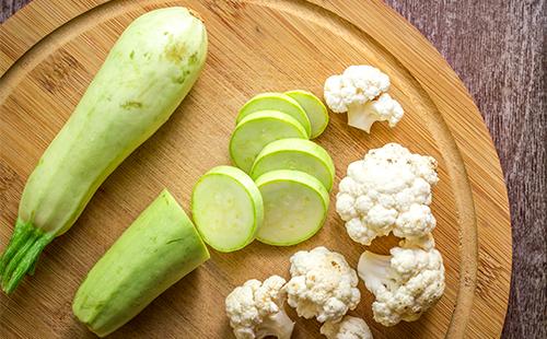 Zucchine e cavolfiore affettati su una tavola di legno