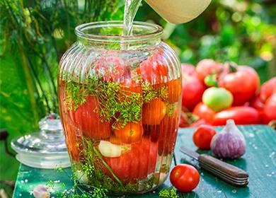 Pomodori d'inscatolamento con le erbe in un barattolo