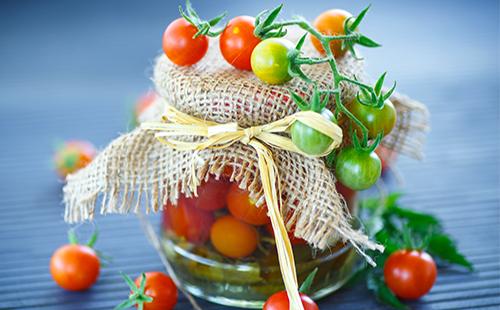 Pomodori ciliegia verdi e rossi in un barattolo