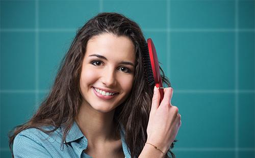 Giovane donna che pettina i suoi capelli