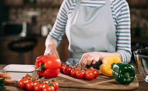 La donna taglia i pomodori e i peperoni in un'insalata