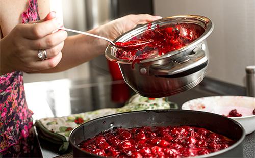 La donna sta cucinando la marmellata di amarene