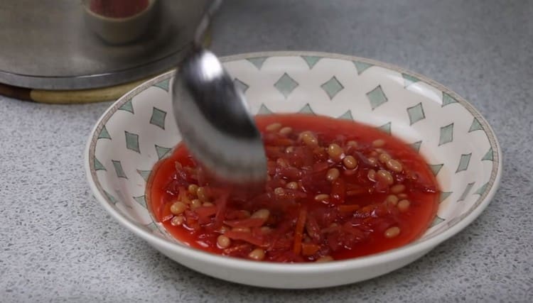 Versare il borsch in piatti porzionati.