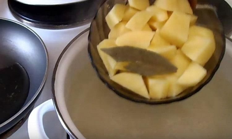 Riso e patate insieme alle foglie di alloro vengono inviati nella padella.