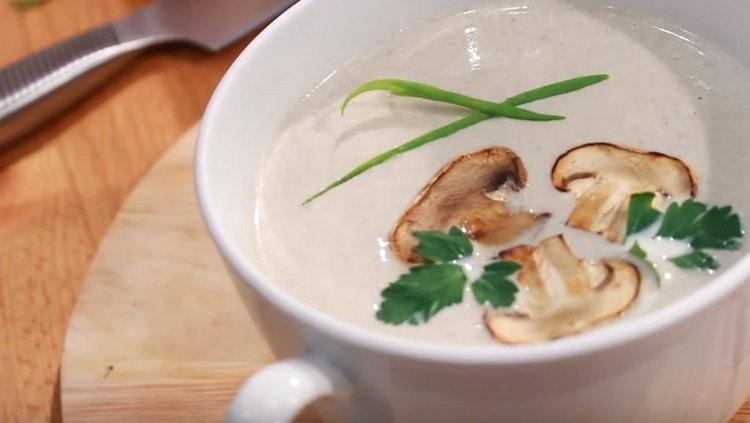 Zuppa di funghi champignon con panna, servita, condita con fette di funghi tostati. così come rametti di prezzemolo.