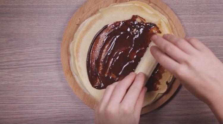 Distribuiamo una fetta di banana e la avvolgiamo in un pancake ricoperto di cioccolato.