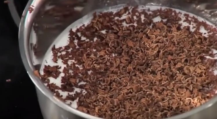 Versare le gocce di cioccolato nel latte caldo, aggiungere lo zucchero.