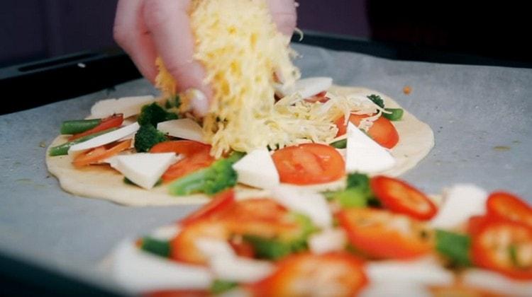 Cospargere la pizza con formaggio grattugiato e mettere in forno.