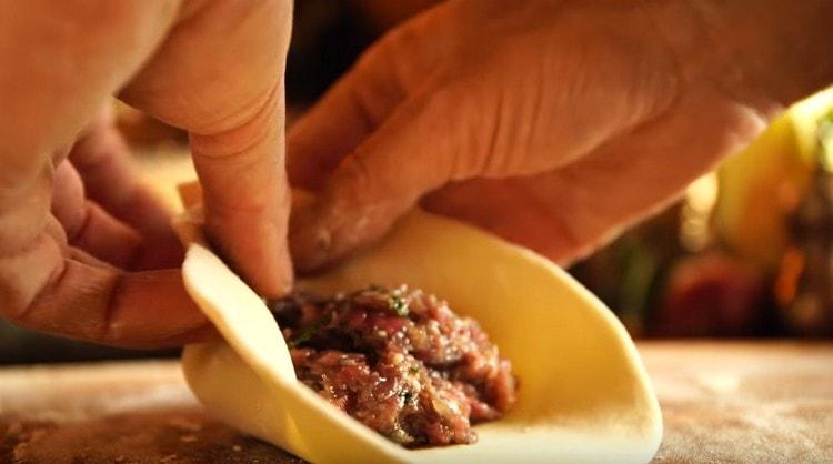 Metti un cucchiaio di carne macinata al centro di ogni torta e raccogli l'impasto con un sacchetto.