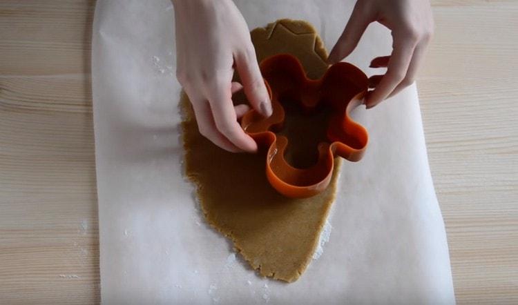 Taglia i biscotti dall'impasto usando delle formine per biscotti.