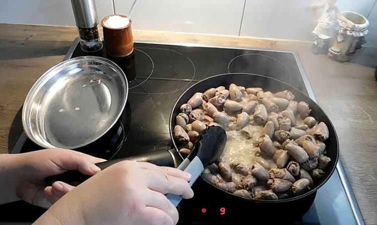 Distribuiamo i cuori di pollo nella padella e friggiamo fino a quando quasi tutto il liquido è evaporato da loro.