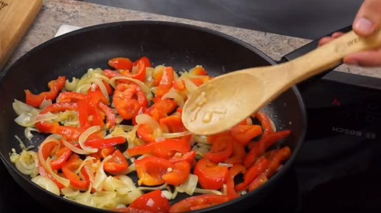 Invece del pollo, ora spargiamo le verdure in una padella e friggiamo fino a quando le cipolle sono trasparenti.