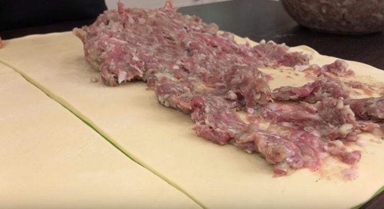 Per ogni metà dell'impasto distribuiamo la carne macinata con uno strato uniforme, ritirandoci da un bordo di alcuni centimetri.