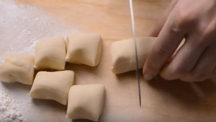 Formiamo una salsiccia da un pezzo di pasta e la tagliamo a pezzi.