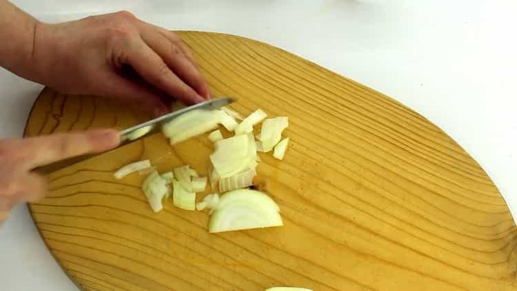 Per preparare le cotolette di carota, tagliare la cipolla