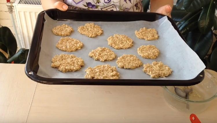 Distribuiamo la farina d'avena con un cucchiaio e la livelliamo con un cucchiaio, formando dei biscotti rotondi.