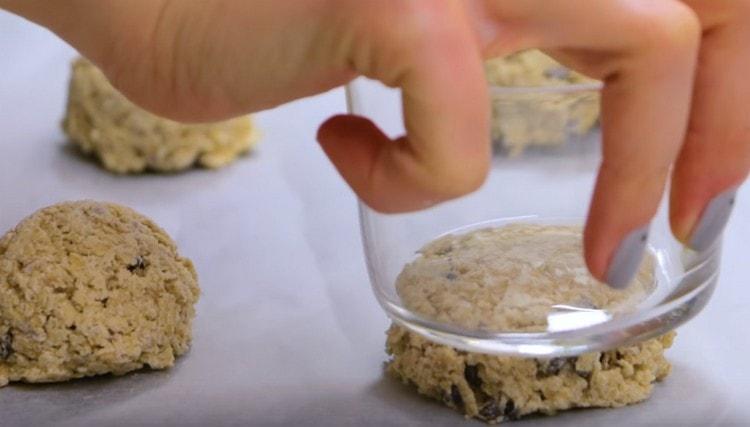 Premi le palline di pasta con un bicchiere, facendo delle torte.