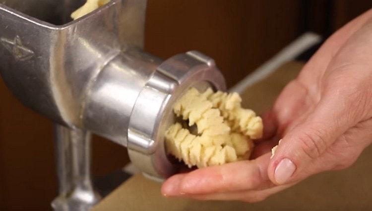 Distribuiamo un pezzo di pasta in un tritacarne e, di conseguenza, otteniamo biscotti ricci.