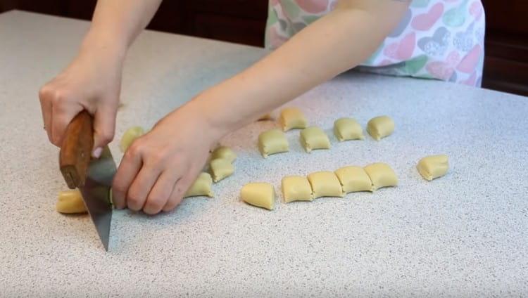 Dall'altro lato dell'impasto, arrotoliamo anche le salsicce e le dividiamo in spazi vuoti per i cappelli.