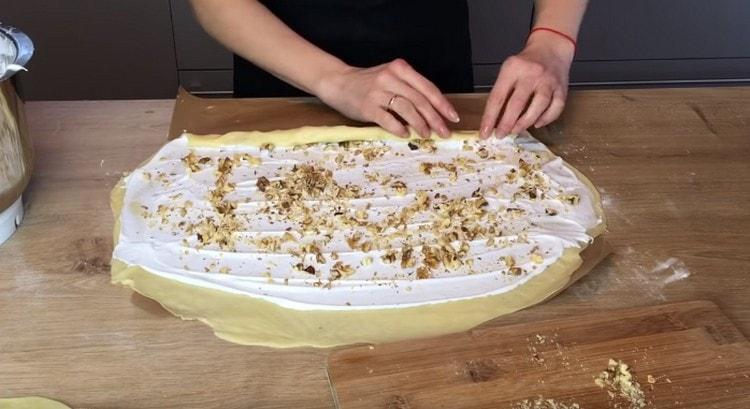 Cospargere lo strato proteico con le noci, quindi trasformare l'impasto in un rotolo.