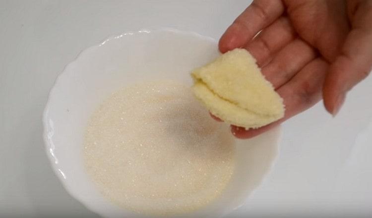 Immergi lo zucchero su un lato dei triangoli della pasta e metti l'altro su una teglia.