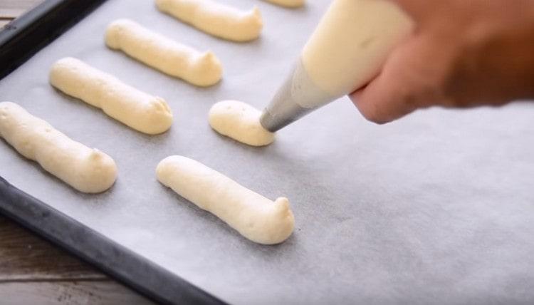 Mandiamo l'impasto in un sacchetto di pasta e stringiamo le dita lunghe e sottili su una teglia coperta di pergamena.