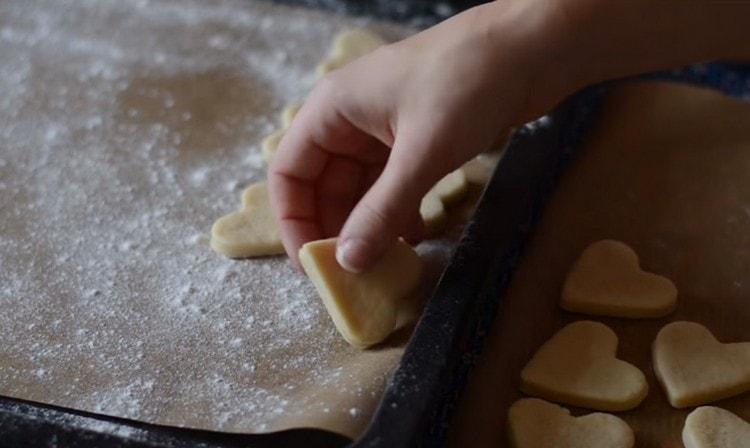 Spostiamo i biscotti su una teglia, ricoperti di pergamena e cosparsi di farina, e li inviamo al forno.