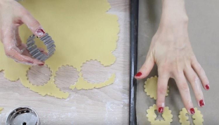 Dall'impasto tagliamo le basi per i biscotti e le cime con gli stampi, in cui dovrebbero esserci buchi ricci.