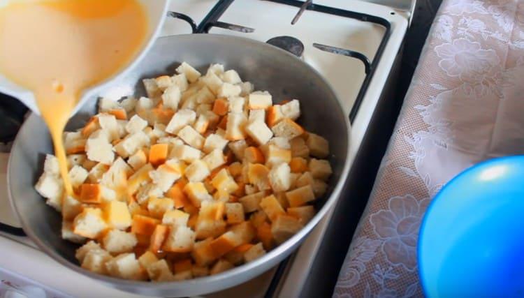 Metti le fette di pagnotta nella padella e riempile uniformemente con la massa di uova.