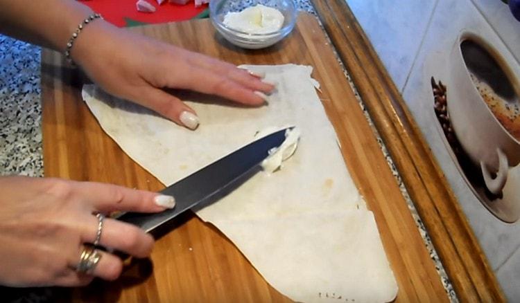 Ungere una parte di pane pita con crema di formaggio.