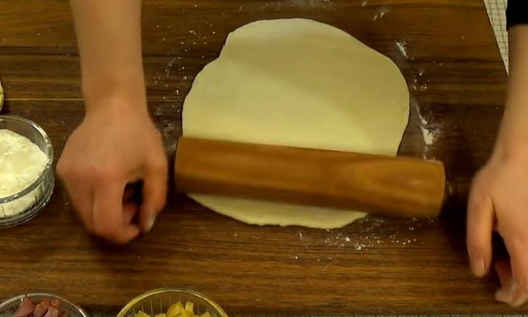 Quando l'impasto viene fuori, dividerlo a metà e stendere ogni parte con un mattarello.